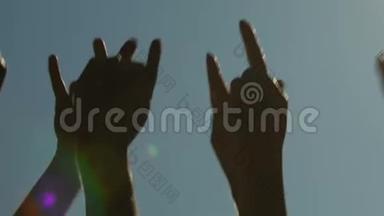 男女双方举起手，在露天摇滚音乐会上向音乐挥手